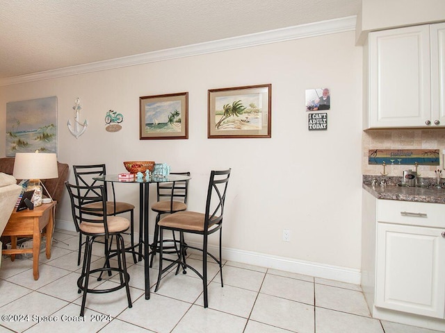 tiled dining area featuring ornamental molding and a textured ceiling