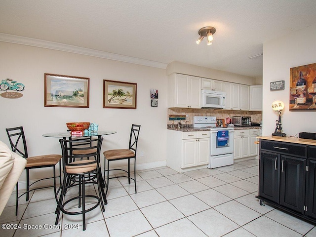 kitchen featuring crown molding, white appliances, backsplash, light tile patterned floors, and white cabinets