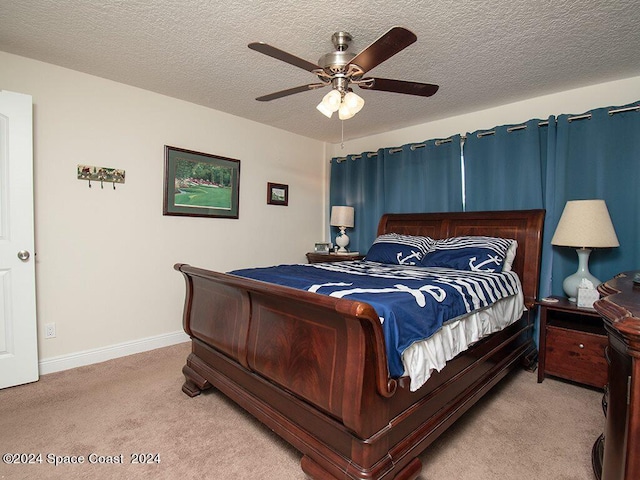 bedroom featuring ceiling fan, light colored carpet, and a textured ceiling