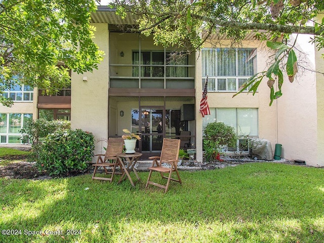 rear view of house featuring a balcony and a lawn