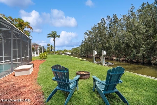 view of home's community featuring a yard, a water view, a fire pit, and a boat dock