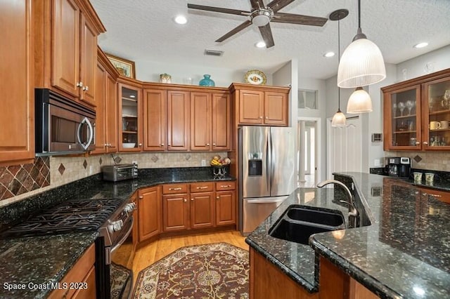 kitchen featuring a sink, decorative light fixtures, brown cabinets, and appliances with stainless steel finishes