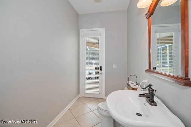 bathroom featuring tile patterned floors, toilet, baseboards, and a sink