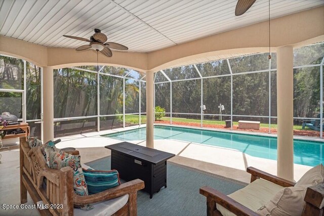 view of pool with glass enclosure, ceiling fan, and a patio