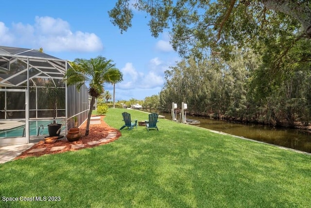 view of yard with a lanai and a water view