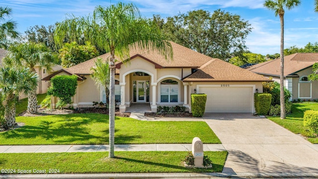 view of front facade featuring stucco siding, driveway, an attached garage, and a front lawn