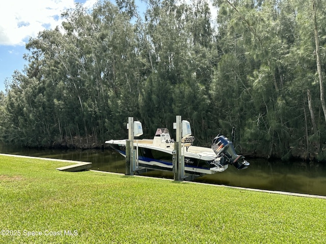 view of dock featuring a lawn, a view of trees, and a water view