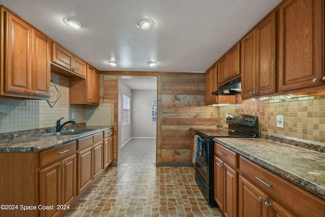 kitchen with black range with electric stovetop, decorative backsplash, sink, and dark stone counters