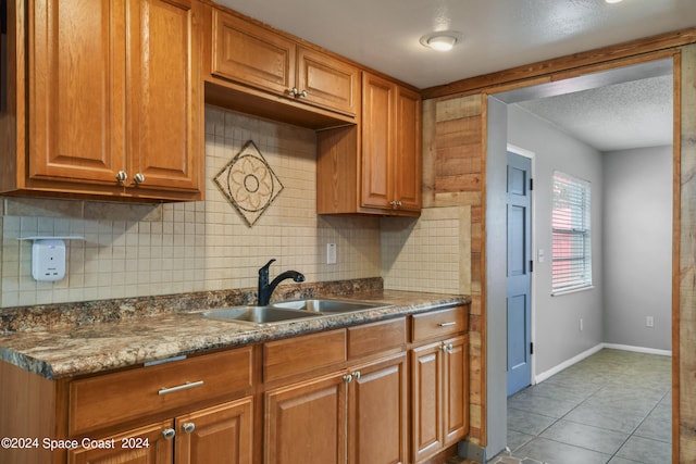 kitchen featuring sink, tile patterned flooring, decorative backsplash, and dark stone counters