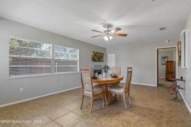 tiled dining room featuring a textured ceiling and ceiling fan