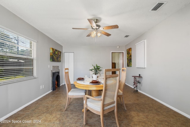 dining space with ceiling fan, dark tile patterned floors, and a textured ceiling