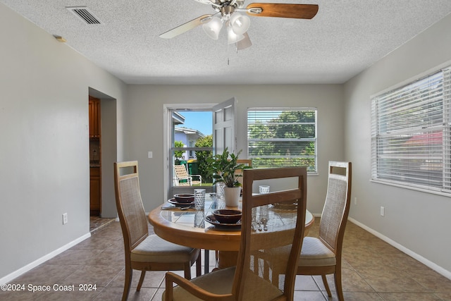 tiled dining room featuring a textured ceiling and ceiling fan