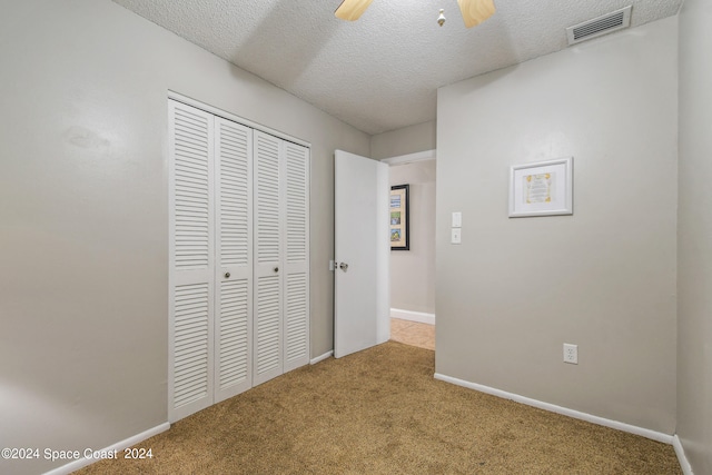 corridor with a textured ceiling and light colored carpet