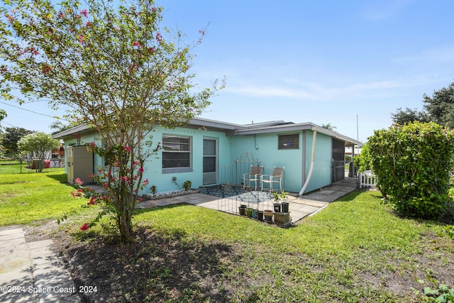 back of property with a patio area and a lawn