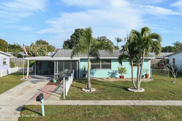 view of front of property featuring a sunroom, a carport, and a front lawn