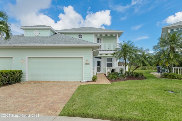 view of front of home featuring a balcony, a garage, and a front yard