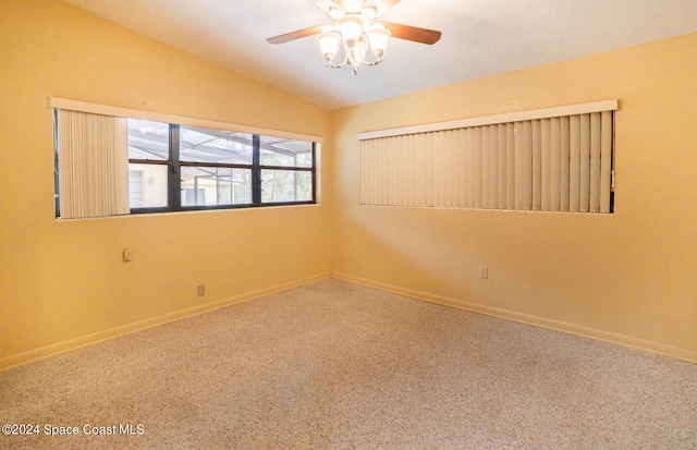 empty room featuring vaulted ceiling, carpet floors, and ceiling fan