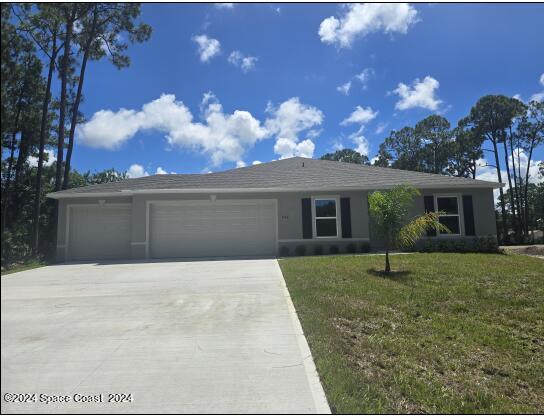 ranch-style home featuring a front yard, an attached garage, stucco siding, and concrete driveway