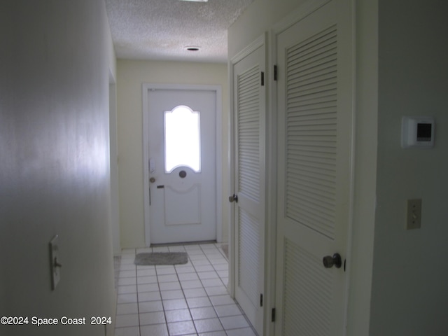 doorway to outside featuring a textured ceiling and light tile patterned floors