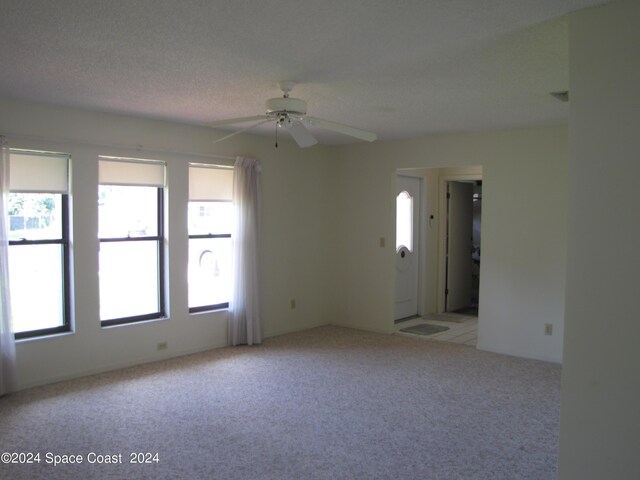 carpeted spare room featuring a textured ceiling and ceiling fan