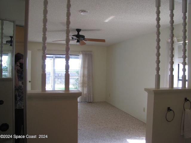 carpeted spare room featuring a textured ceiling and ceiling fan