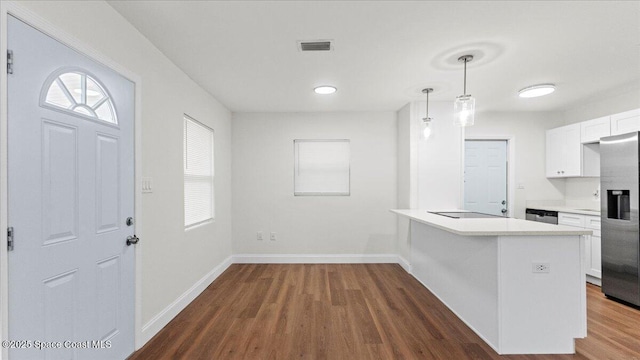 kitchen featuring appliances with stainless steel finishes, dark hardwood / wood-style flooring, kitchen peninsula, pendant lighting, and white cabinets