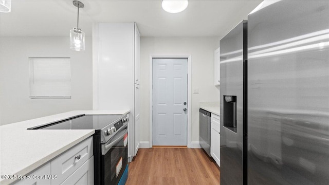 kitchen featuring decorative light fixtures, stainless steel appliances, white cabinets, and light wood-type flooring