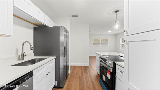 kitchen with hanging light fixtures, white cabinetry, appliances with stainless steel finishes, and sink