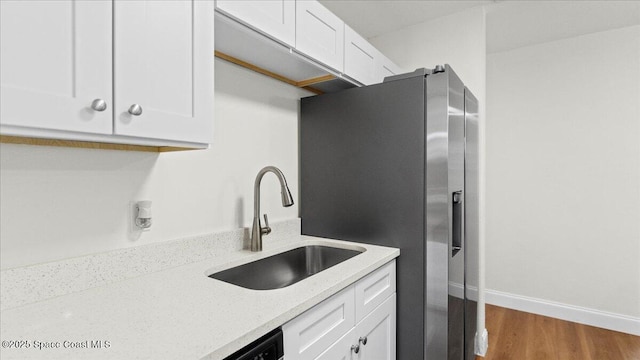 kitchen with dark hardwood / wood-style floors, white cabinetry, sink, light stone counters, and stainless steel refrigerator with ice dispenser