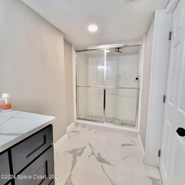 bathroom featuring a shower with shower door and vanity