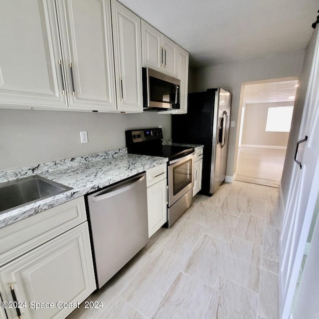 kitchen featuring white cabinetry, stainless steel appliances, and light stone countertops