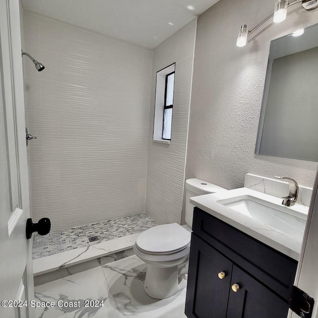 bathroom with tiled shower, toilet, and vanity