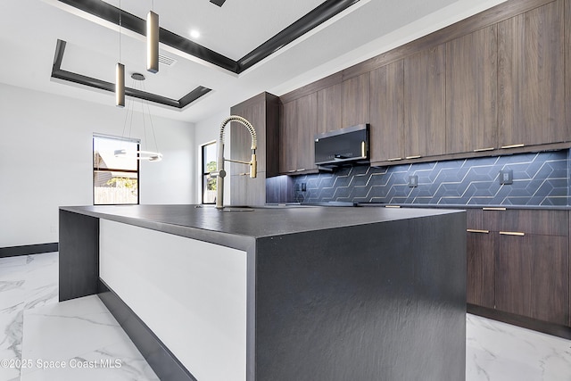 kitchen with a center island, a tray ceiling, backsplash, and decorative light fixtures