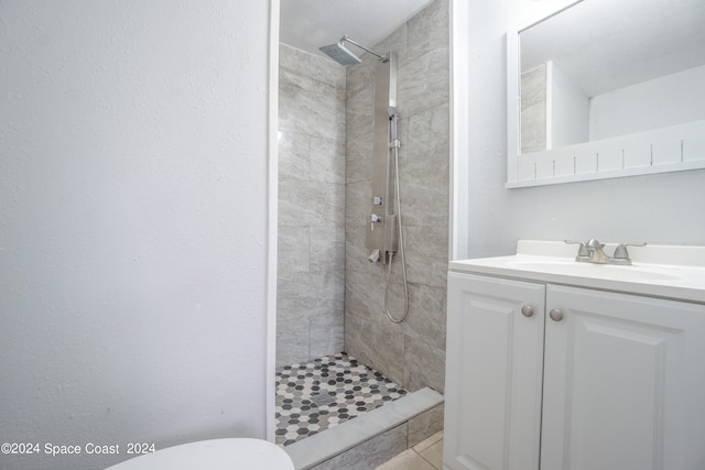 bathroom featuring tiled shower, tile patterned flooring, toilet, and vanity