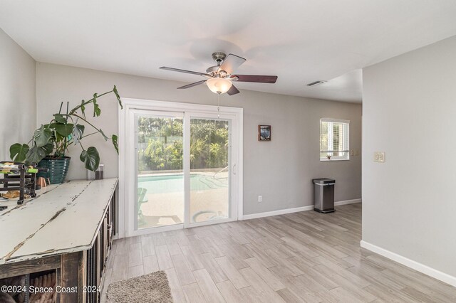 unfurnished office with a wealth of natural light, ceiling fan, and light wood-type flooring