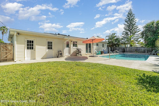 rear view of house with a lawn, a fenced in pool, and a patio