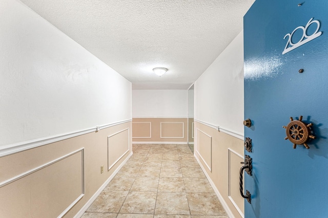 hallway featuring a textured ceiling and light tile patterned floors