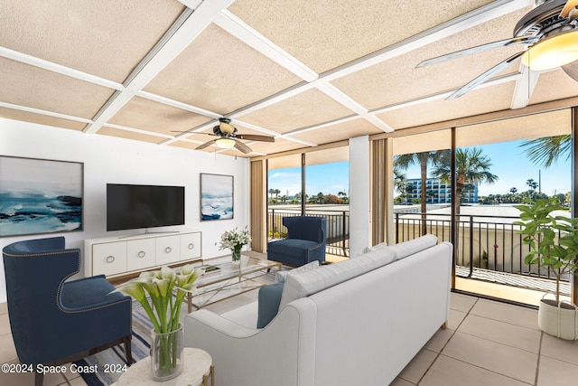 living room with ceiling fan, a wall of windows, light tile patterned floors, and coffered ceiling