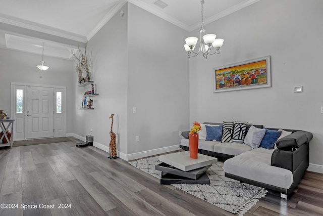 living room featuring a high ceiling, hardwood / wood-style flooring, ornamental molding, and a notable chandelier