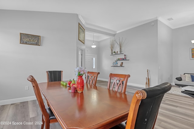 dining room with ornamental molding and light wood-type flooring