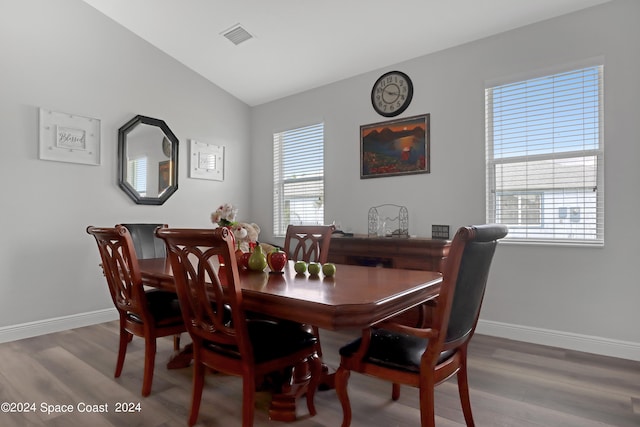 dining room with hardwood / wood-style flooring and vaulted ceiling