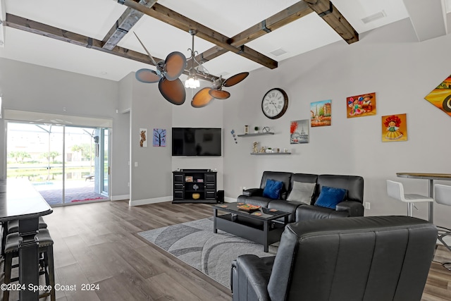 living room featuring hardwood / wood-style flooring, ceiling fan, and a towering ceiling