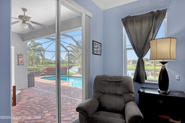 living area featuring a water view, a pool, a wealth of natural light, and crown molding