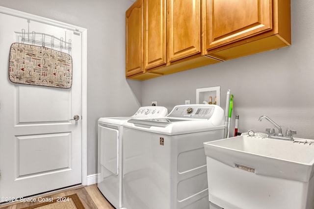 laundry room featuring cabinets, light wood-type flooring, washer and clothes dryer, and sink