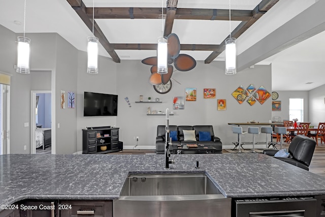 kitchen featuring beam ceiling, sink, dark stone counters, decorative light fixtures, and hardwood / wood-style flooring