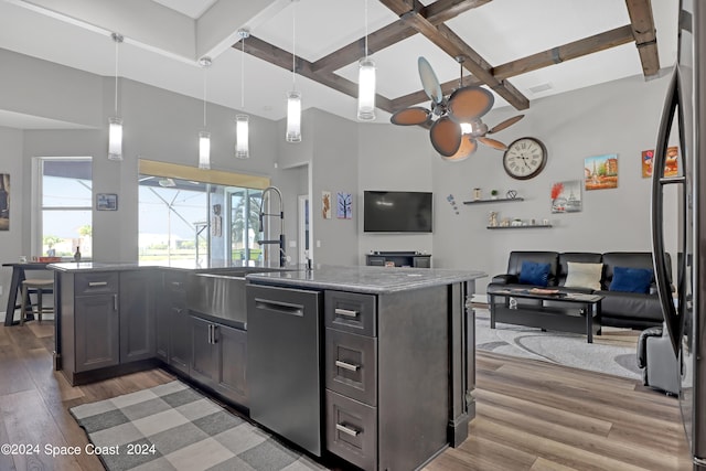 kitchen with a center island with sink, light hardwood / wood-style flooring, light stone countertops, decorative light fixtures, and stainless steel appliances