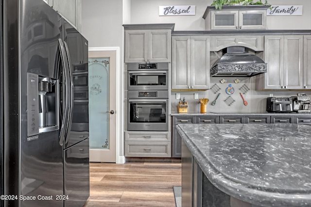 kitchen featuring appliances with stainless steel finishes, light hardwood / wood-style floors, gray cabinets, and custom exhaust hood