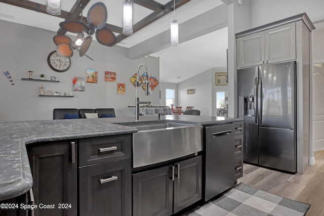 kitchen with appliances with stainless steel finishes, ceiling fan, sink, lofted ceiling with beams, and light hardwood / wood-style floors