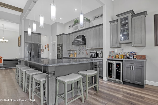 kitchen with wine cooler, pendant lighting, custom range hood, and hardwood / wood-style flooring