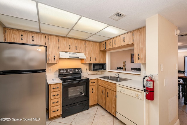 kitchen with sink, a paneled ceiling, black appliances, and light tile patterned flooring